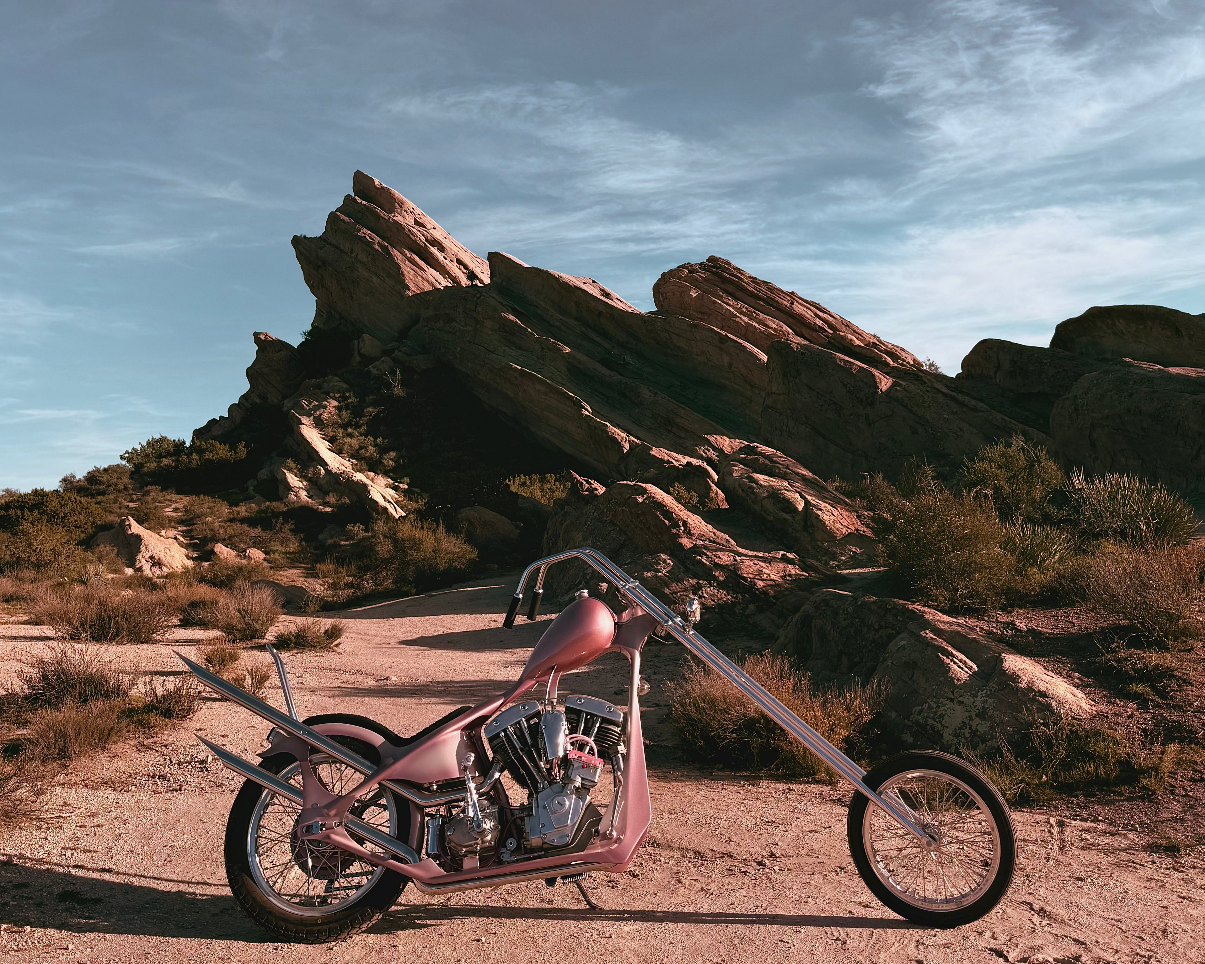 Pink motorcycle in a desert landscape with rocky formations